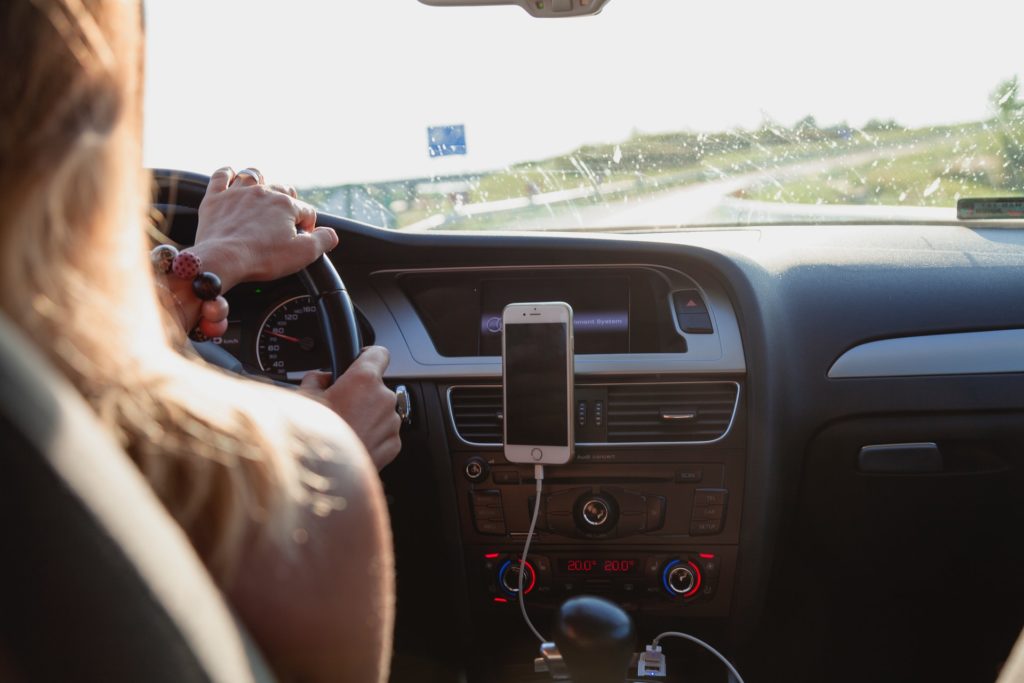 Woman driving with cellphone on dashboard