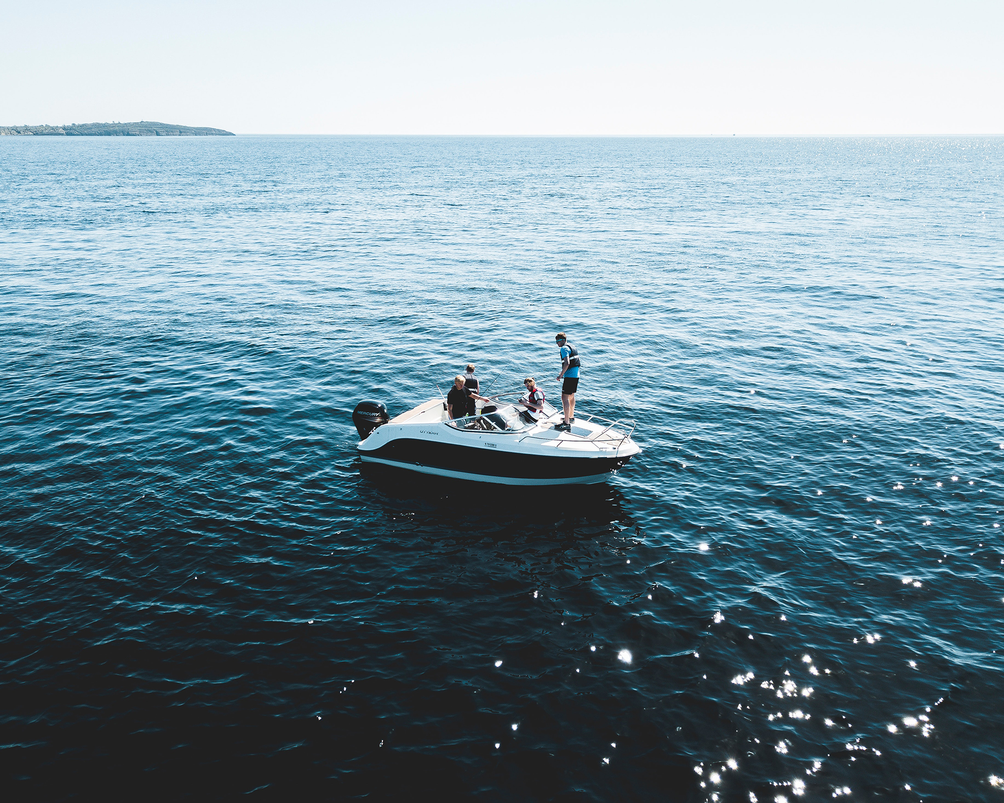 Three people on a white speedboat in a summer day.