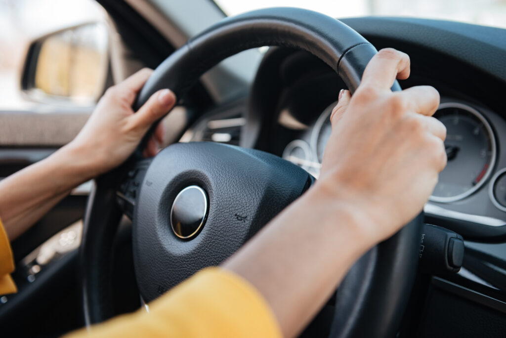 Close-up of female hands on steering wheel while driving a car