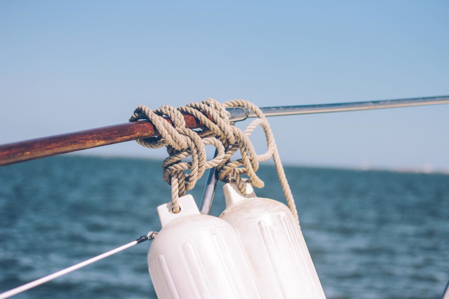 Boat fenders tied with rope on a railing near water in British Columbia. 