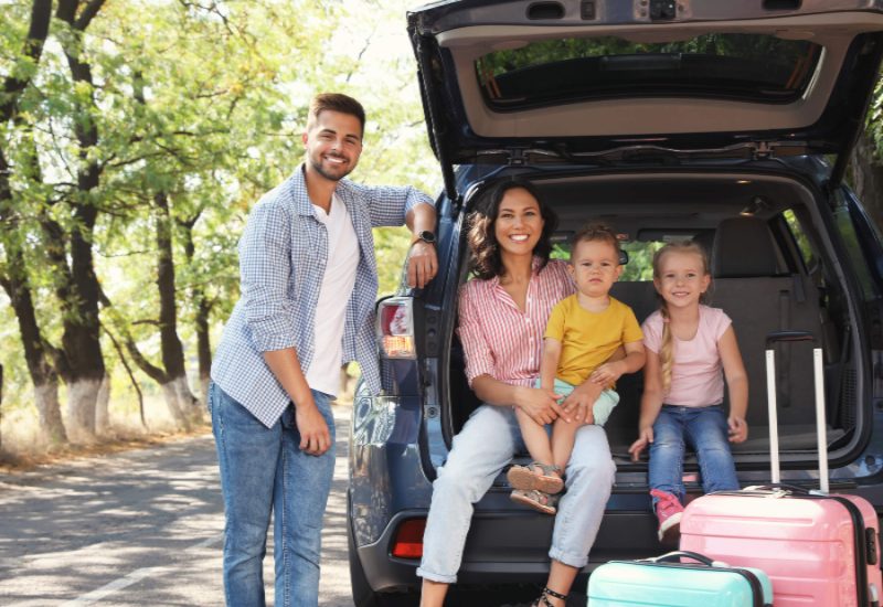 Happy family on a road trip with suitcases.