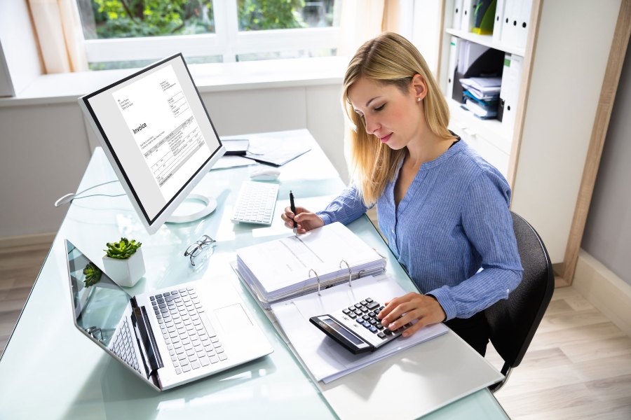 Woman at desk doing paperwork using calculator