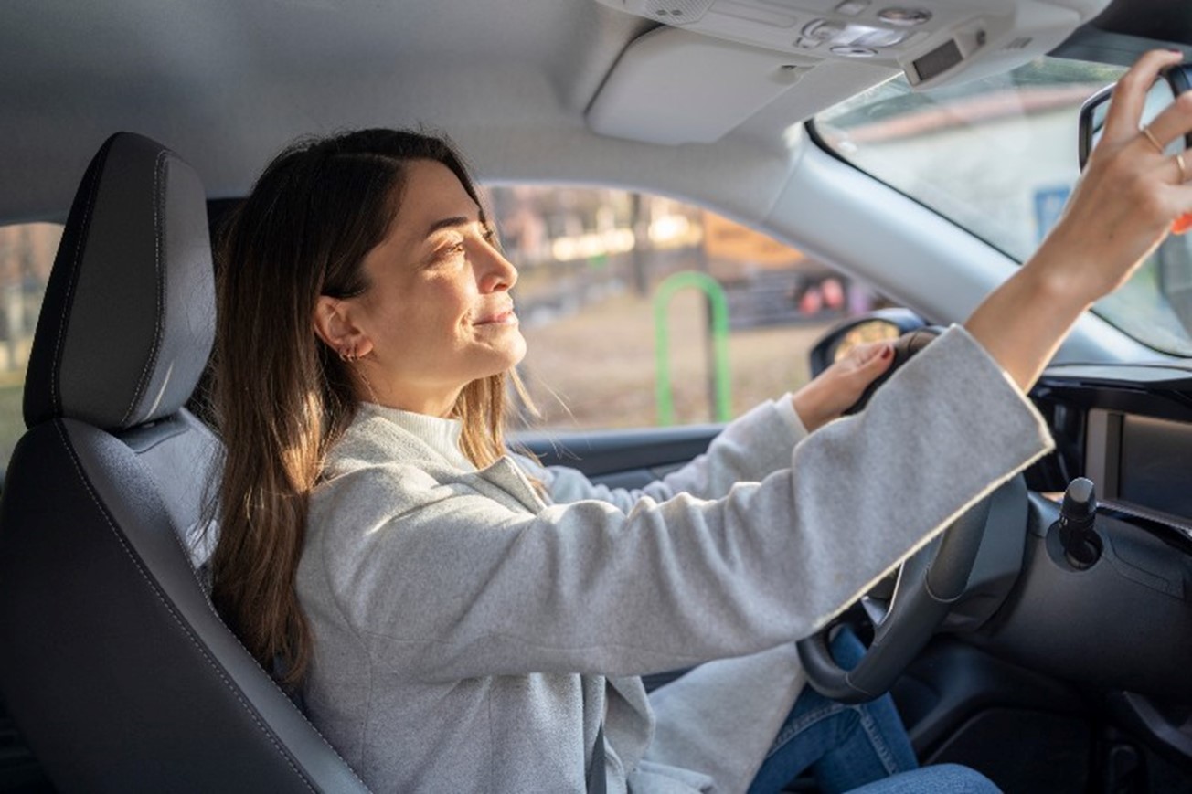 A woman adjusting the rearview mirror in a car by Johnston Meier Insurance Agencies Group